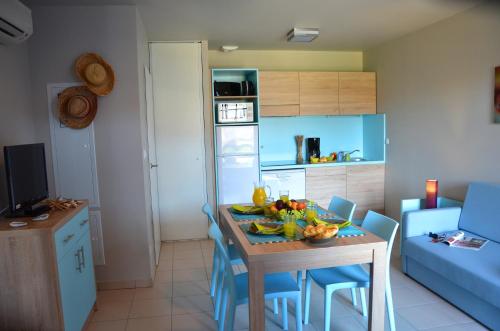 a kitchen with a table with a bowl of fruit on it at Lagrange Grand Bleu Vacances – Résidence La Grenadine in Marseillan
