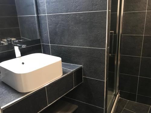 La salle de bains est pourvue de carrelage noir, d'un lavabo et d'une douche. dans l'établissement Petit Jean, à Saint-Tropez