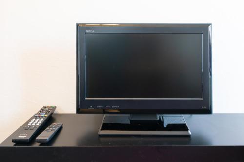 a computer monitor and two remote controls on a desk at SONIC APARTMENT HOTEL in Dazaifu