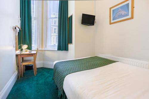 a bedroom with a bed and a desk and a window at London Town Hotel in London