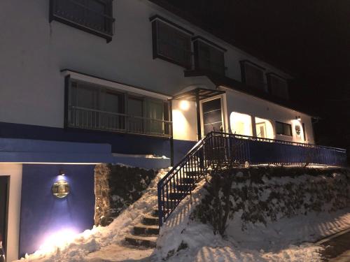a house with a staircase in the snow at night at Oyado Zen in Kusatsu
