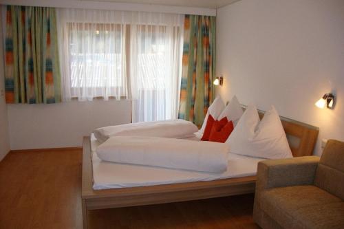 1 Schlafzimmer mit 2 Betten mit weißen Kissen und einem Sofa in der Unterkunft Appartements Schwoagerhof in Fügen