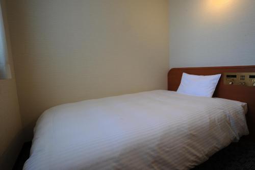 a bed in a room with a white bedsheet at Suizenji Comfort Hotel in Kumamoto
