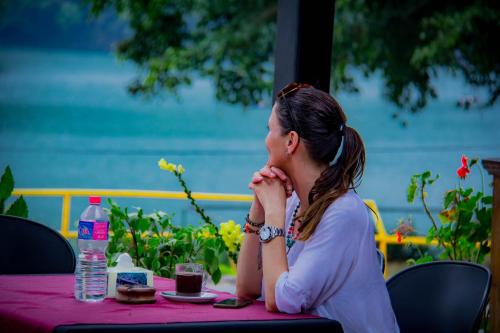 a woman sitting at a table with her hand to her face at Lake View Resort in Pokhara