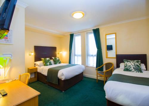 a hotel room with two beds and a desk at London Town Hotel in London