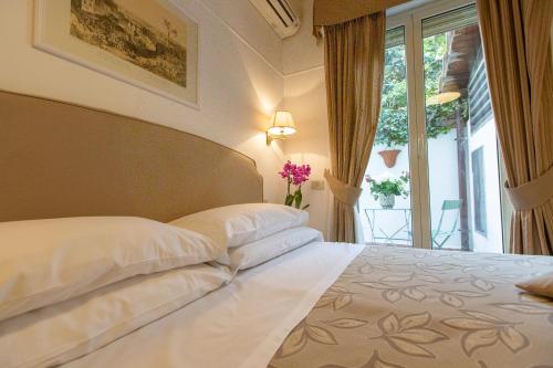 sypialnia z łóżkiem z białą pościelą i oknem w obiekcie Hotel Modigliani w Rzymie