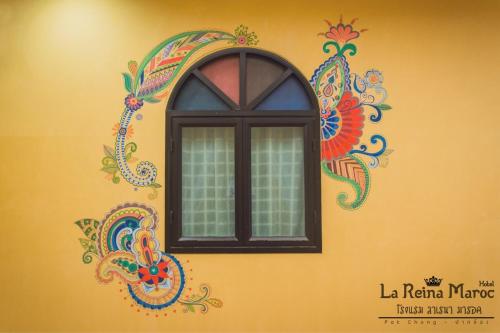 a window on the side of a yellow wall with a painting at La Reina Maroc Hotel ปากช่อง เขาใหญ่ in Pak Chong