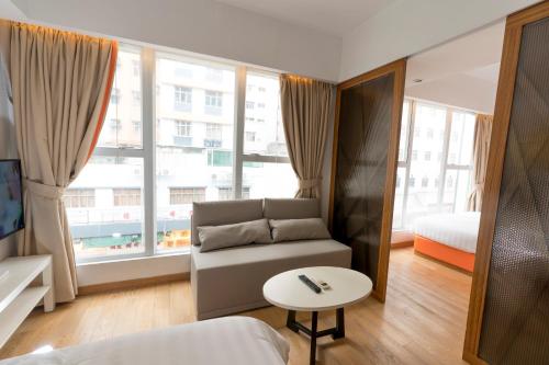 uma sala de estar com um sofá, uma mesa e janelas em Homy Residence em Hong Kong