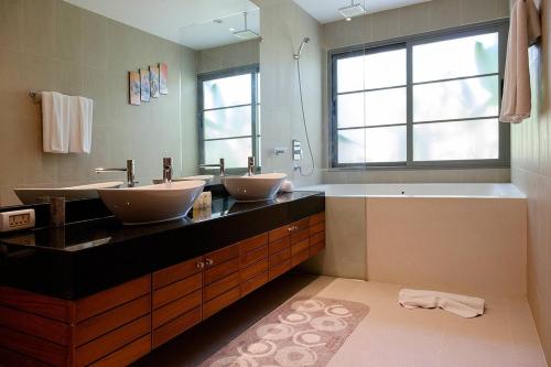 uma casa de banho com 2 lavatórios, uma banheira e uma janela em Luxury 3br Pool Villa Walk To Bangtao Beach em Praia de Bang Tao