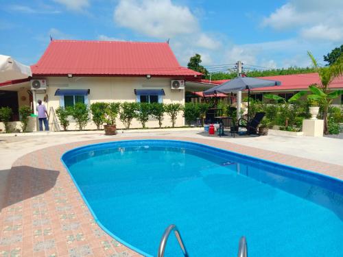 a swimming pool in front of a house with a red roof at Private 2 bedroom villa with Swimming pool Tropical gardens Fast Wifi smart Tv in Ban Sang Luang