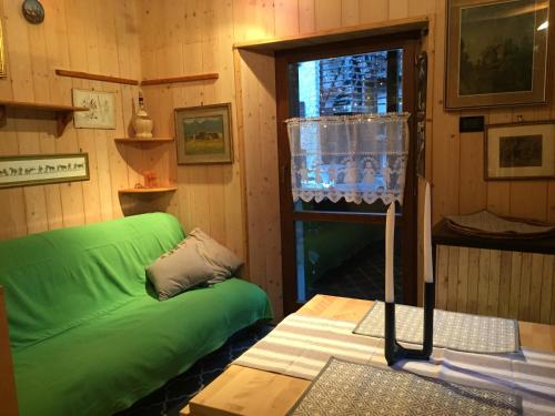 a living room with a green couch and a window at La Tana dell'Orso in Forni di Sopra
