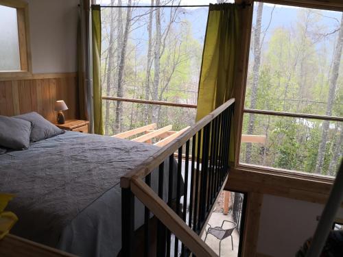 1 dormitorio con 1 cama y balcón con ventanas grandes. en Loft Canelo - con hot tub exclusivo, cercano a termas y lago, en Coñaripe