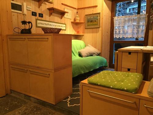 a room with two beds and a green ottoman at La Tana dell'Orso in Forni di Sopra