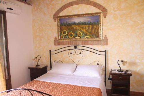 a bedroom with a bed with a painting on the wall at L'Uliveto in Reitano