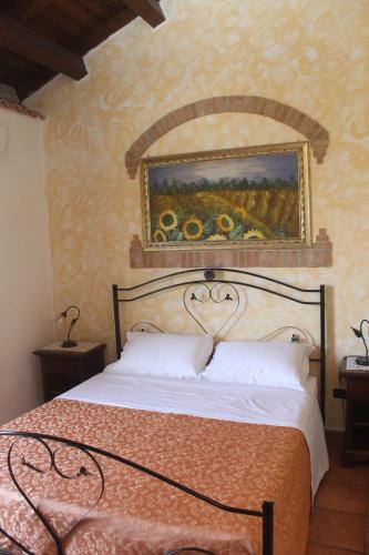 a bedroom with a bed with a painting on the wall at L'Uliveto in Reitano