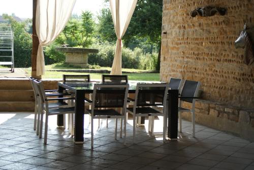 une table à manger avec des chaises et un mur en pierre dans l'établissement Le Moulin de Champagne, à Viriat