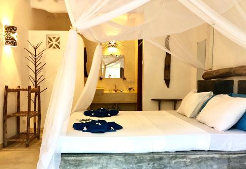 a bedroom with a white bed with a canopy at Zanzistar Lodge in Jambiani