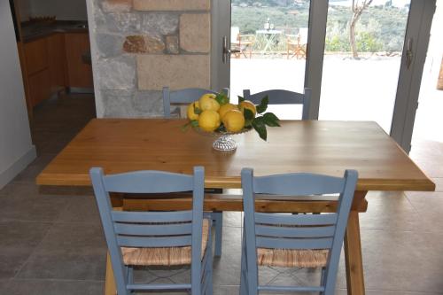 a wooden table with two chairs and a bowl of fruit at Athina's Stone House in Kardamyli in Kardamili