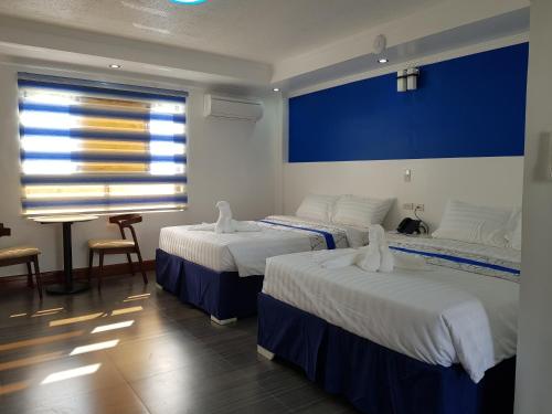 a room with three beds and a blue wall at Santiago Cove Hotel and Restaurant in Santiago