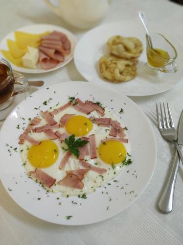 a plate of food with eggs and bacon on a table at Predslava Hotel in Kyiv