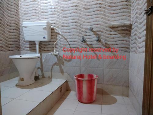 a bathroom with a toilet and a trash can at Nataraj Hotel and Boarding in Barddhamān