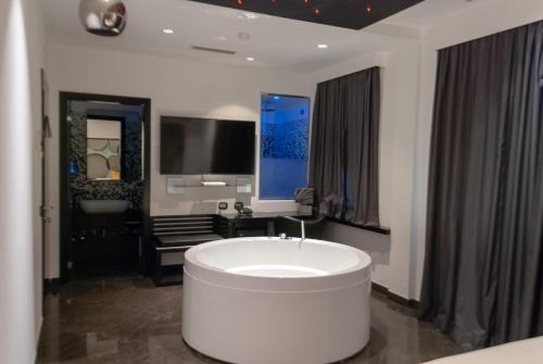 a bathroom with a large white tub and a tv at JC Hotel in Rome