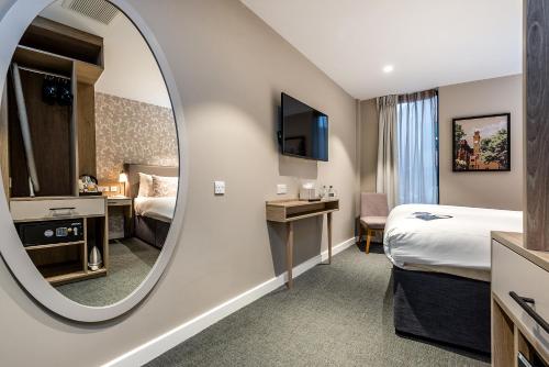 a hotel room with a bed and a mirror at Edgbaston Park Hotel Birmingham in Birmingham