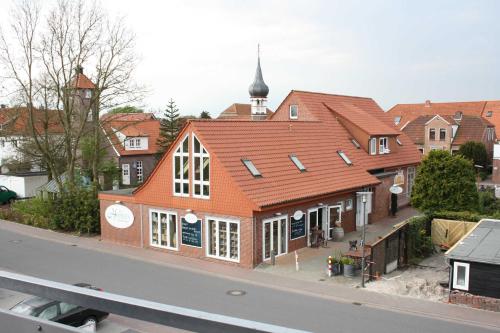 ein Gebäude mit einem orangenen Dach an der Straßenseite in der Unterkunft Ferienwohnung Perlmutt in Hooksiel