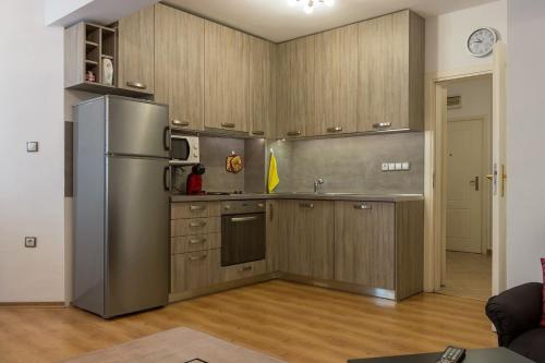 cocina con armarios de madera y nevera de acero inoxidable en GLORIOUS - 2-Bedroom apartment near Youth Hill, en Plovdiv