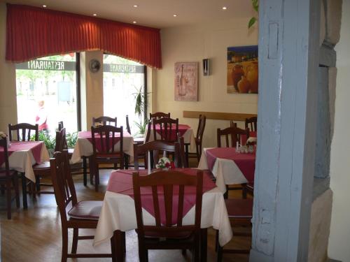 a restaurant with tables and chairs with red and white tablecloths at Gasthof & Fleischerei Endler in Rheinsberg