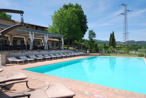 a large swimming pool with lounge chairs next to a building at Spoleto by the pool in Spoleto