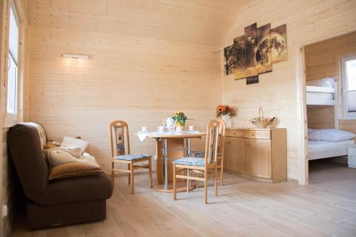 a living room with a table and chairs and a bed at Domki Letniskowe Biała Perła in Jezierzany