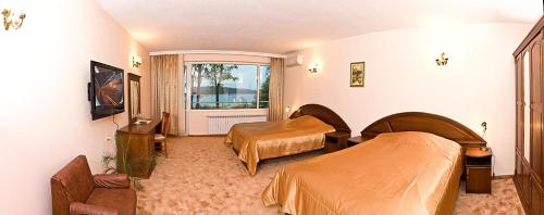 Cette chambre comprend 2 lits et une fenêtre. dans l'établissement Хотел ЗЛАТНА КОТВА, à Kazanlak