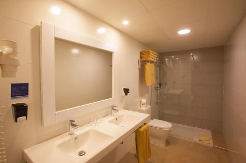 ein Badezimmer mit einem Waschbecken, einem WC und einem Spiegel in der Unterkunft Grupotel Orquidea in San Agustín