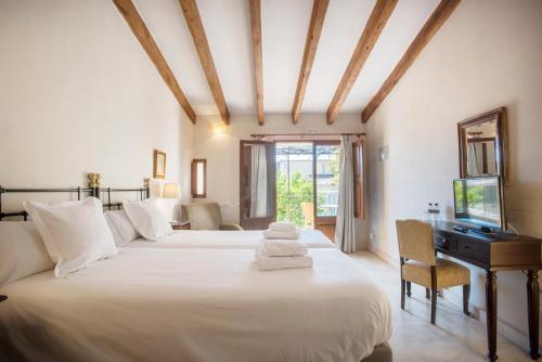 a bedroom with two beds and a desk and a television at Sa Bisbal - Turismo de interior in Selva