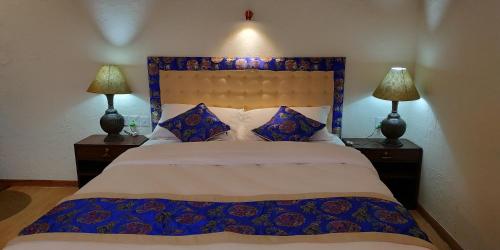 a bedroom with a blue and white bed with two lamps at Heranya La:Ku in Pātan