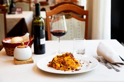a plate of pasta and a glass of wine on a table at JR Hotels Bologna Amadeus in Bologna