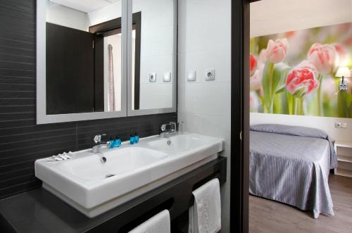 a bathroom with a white sink and a bed at Hotel Amaraigua – All Inclusive – Adults Only in Malgrat de Mar