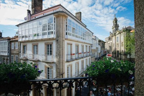 - un grand bâtiment blanc avec des fenêtres donnant sur une rue de la ville dans l'établissement Hotel Arco de Mazarelos, à Saint-Jacques-de-Compostelle