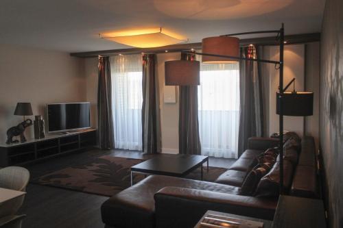 a living room with a couch and a tv at Parkhotel Heidehof Long Stay in Ingolstadt