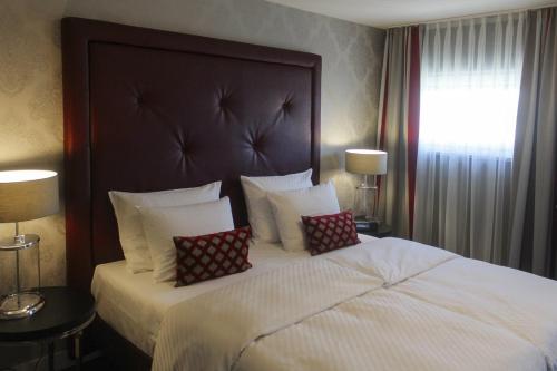 a bedroom with a large bed with two pillows on it at Parkhotel Heidehof Long Stay in Ingolstadt