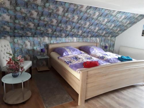 1 dormitorio con cama de madera y papel pintado con motivos florales en Ferienhaus Luise, en Sebnitz