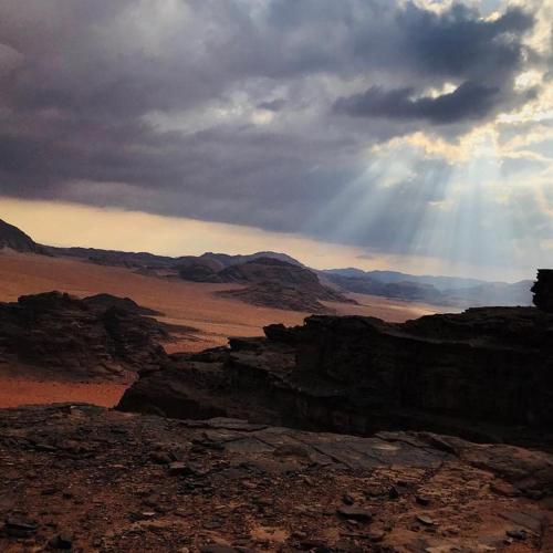 widok pustyni ze słońcem świecącym przez chmury w obiekcie Wadi Rum Excursions w mieście Wadi Rum