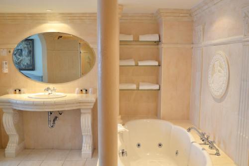 een badkamer met een bad, een wastafel en een spiegel bij Fletcher Hotel - Restaurant Heiloo in Heiloo