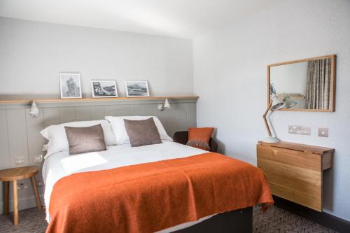 a bedroom with a bed with an orange blanket at Bosville Hotel in Portree