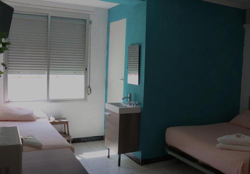 a bedroom with two beds and a sink and a window at Pensión Fortea in Zaragoza