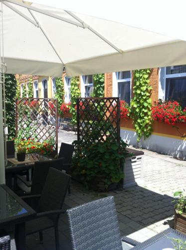a patio with a white umbrella and chairs and flowers at An der Porzellan-Manufaktur Pension in Meißen