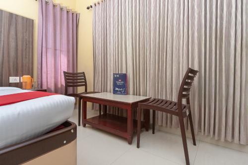 a bedroom with a bed and a table and chairs at Hotel Skyark in Kanyakumari
