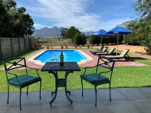 a table with two chairs and a bottle of wine at Vine Guesthouse in Stellenbosch