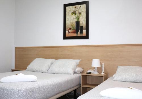a bedroom with two beds and a picture on the wall at Hostal Milmarcos in Zaragoza